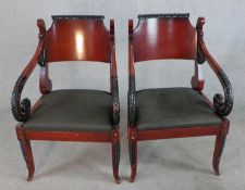A pair of Regency style mahogany open arm chairs, with drop in seats, the scroll arms with carved