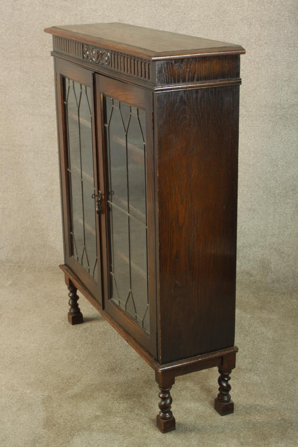 An early 20th century carved oak twin door leaded glass display cabinet, raised on turned supports - Image 6 of 9