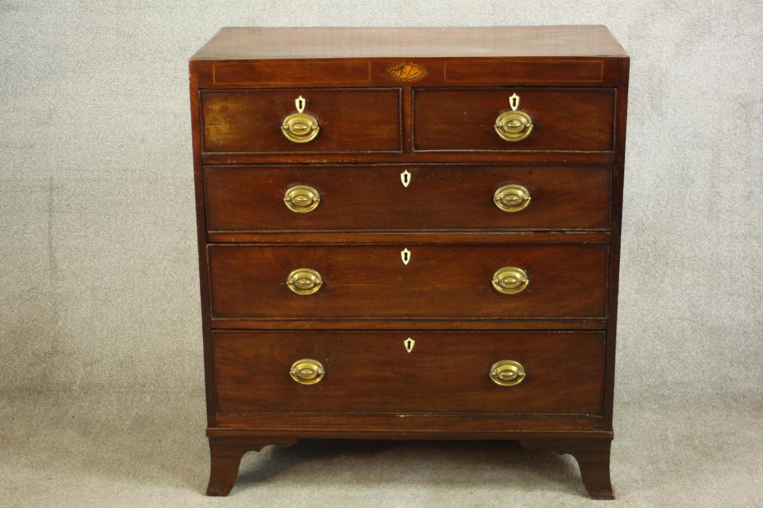 A Georgian inlaid mahogany chest of two short over three graduating drawers, raised on shaped