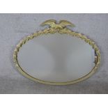 A 20th century oval gilt framed mirror mounted with leaf and eagle decoration. H.77 W.96cm