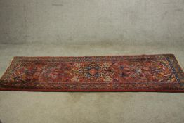 A 20th century red ground Hamadan runner, with floral decoration within a geometric border.