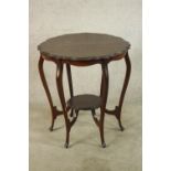 A late Victorian mahogany two tier occasional table, raised on six cabriole supports terminating