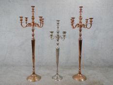 A contemporary pair of copper effect five branch floor standing candelabra, raised on stepped