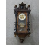 A 19th century mahogany and walnut Vienna style wall clock, with turned finials, the glass door