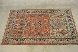 A 20th century red ground Persian woollen rug, with all over floral decoration within geometric
