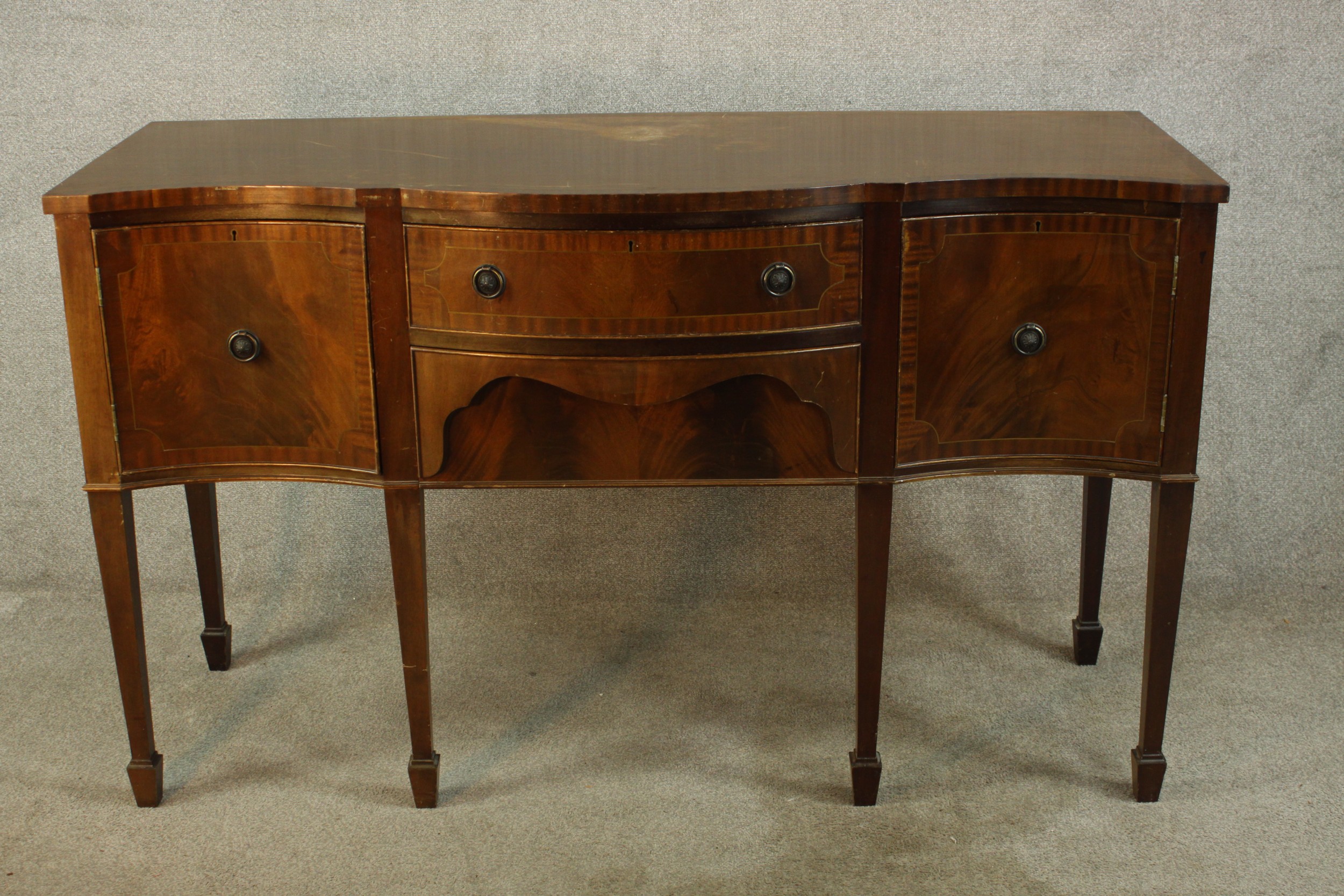 A Regency style mahogany serpentine fronted sideboard, with two central doors flanking two door