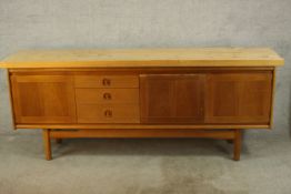 A mid 20th century teak sideboard, with three drawers and three cupboard doors, raised on tapering