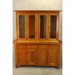 A contemporary, possibly cherrywood, kitchen dresser, with four glass panel doors above four short