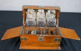 An early 20th century oak and brass three bottle decanter/tantalus box, with three glass