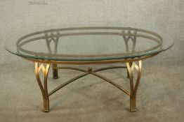 A 20th century gilt metal and glass oval topped table, raised on pierced supports united by