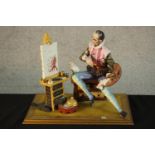 A 20th century Italian Capodimonte pottery figure of an artist painting with a cat, raised on