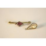 A brass Amethyst paste set bar brooch and fresh water pearl bead in a yellow metal cage. L.4cm (