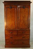 A 19th century mahogany twin door linen press, opening to reveal clothes slides, on two short over