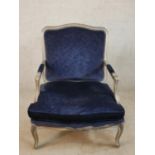 An early 20th century silver painted French style open armchair, with blue upholstered stuff over