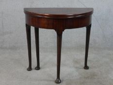 A 19th century mahogany demi lune foldover table, raised on tapering supports terminating on pad