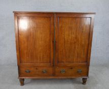 A 19th century mahogany twin door linen press, opening to reveal clothes slides, standing on two