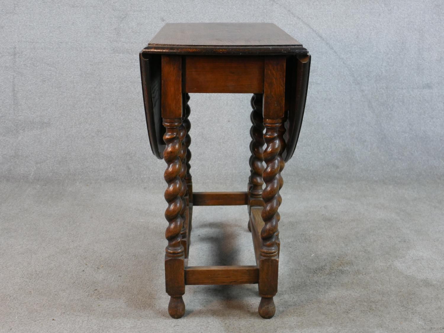 An early 20th century oak drop leaf gate leg table, raised on barley twist supports terminating in - Image 3 of 5