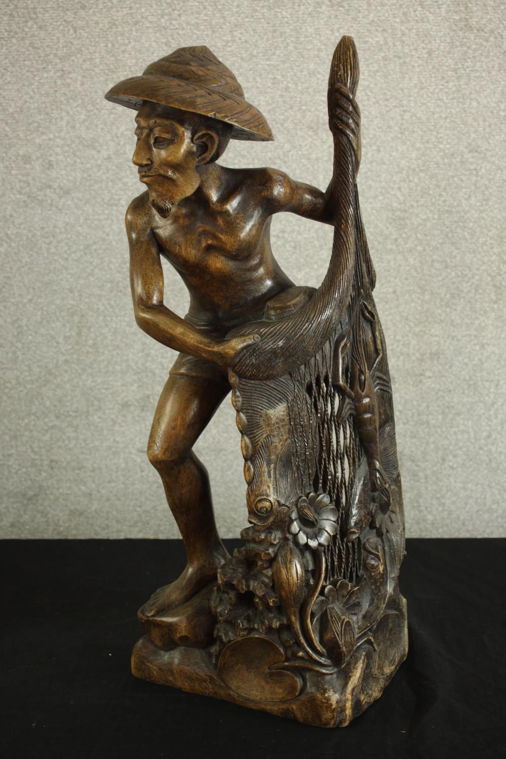 An early 20th century carved Chinese hardwood fisherman, raised on naturalistic base. H.63 W.25 D.