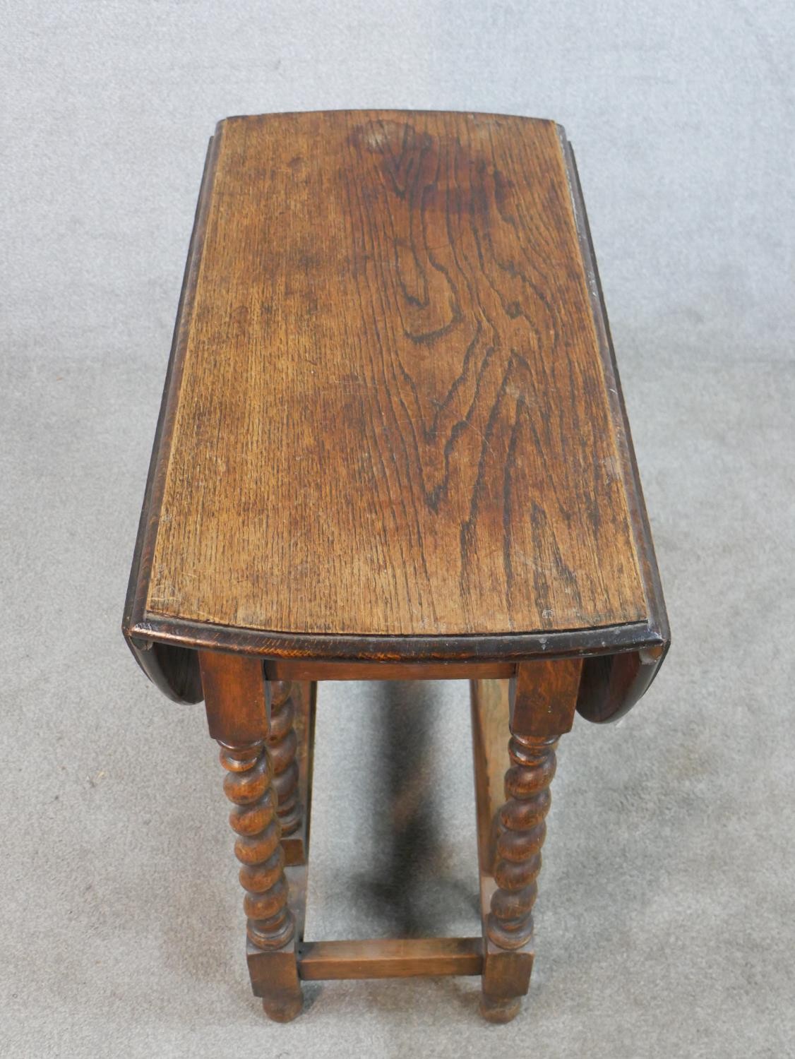 An early 20th century oak drop leaf gate leg table, raised on barley twist supports terminating in - Image 4 of 5