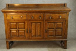 A 20th century carved oak three drawer and three cupboard door sideboard with brass drop handles,