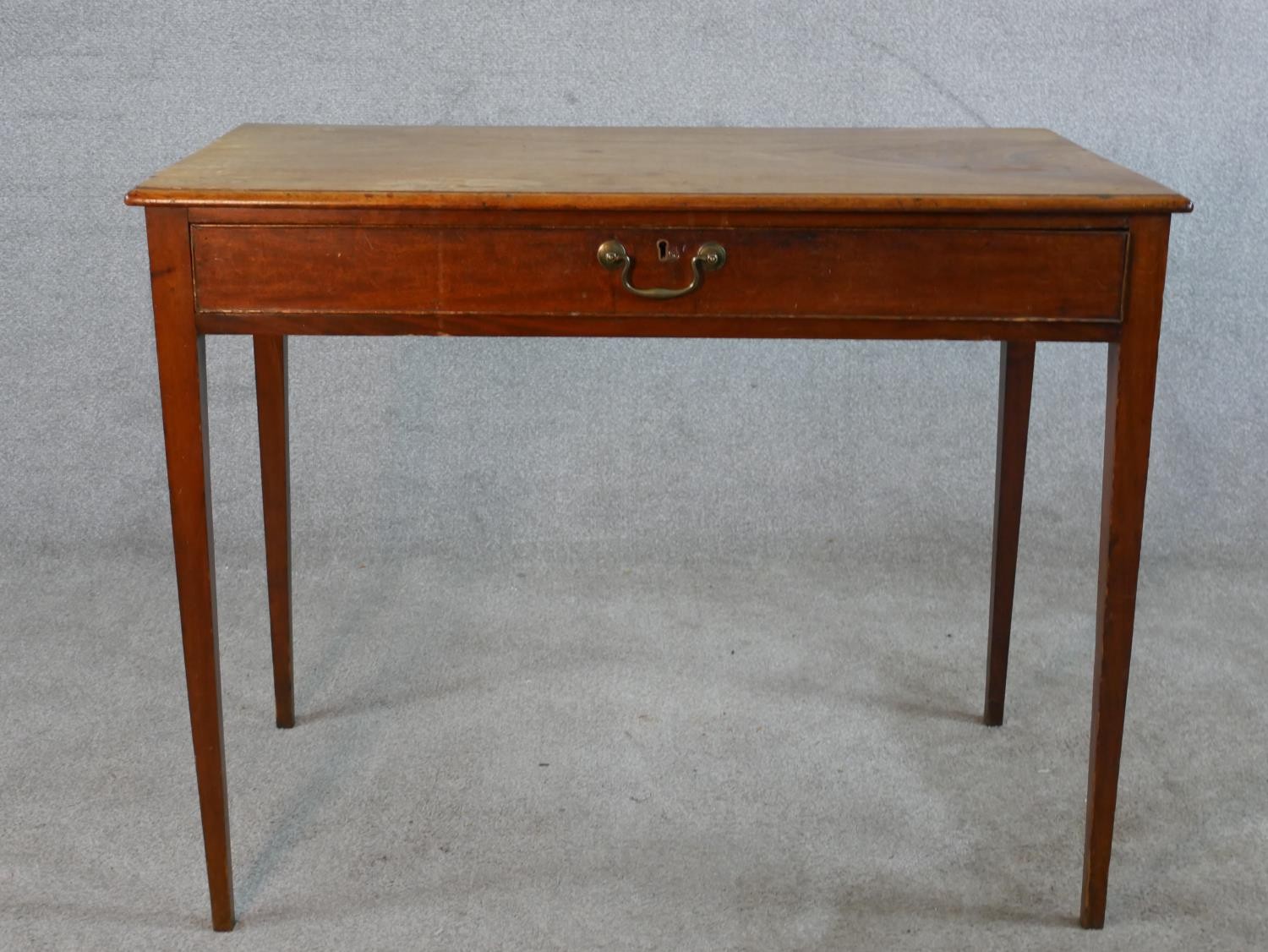A 19th century mahogany single drawer side table with brass swing handle, raised on square