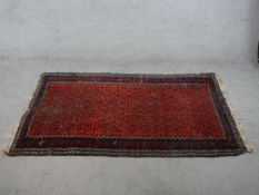 A 20th century red ground Persian rug, with all over geometric pattern, within geometric border. H.