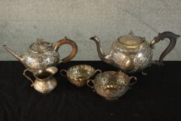 A 19th century white metal bullet shaped teapot, with floral and crest decoration and wooden handle,