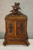 A 19th/early 20th century carved Black Forest table cabinet, surmounted with a pair of pheasants,