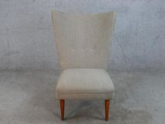 A mid 20th century Danish teak framed nursing chair with button back upholstery, raised on four