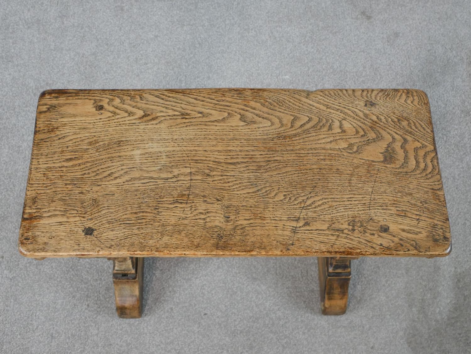 A late 19th/early 20th century stained oak stool, raised on carved trestle supports with block feet. - Image 2 of 5