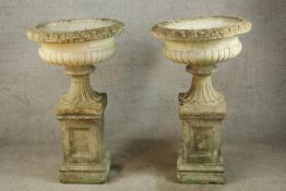 A pair of 20th century carved stone fluted urn shaped garden planters, each raised on square