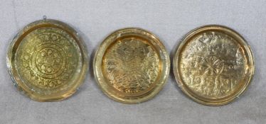 Three 20th century Indian embossed brass circular trays. Dia. 49cm (largest)