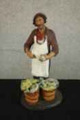A 20th century Russian painted pottery figure of a a fishmonger, impressed marks. H.25 W.13 D.11cm.