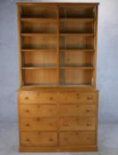 An early 20th century golden oak dresser with open shelves above eight short drawers and turned