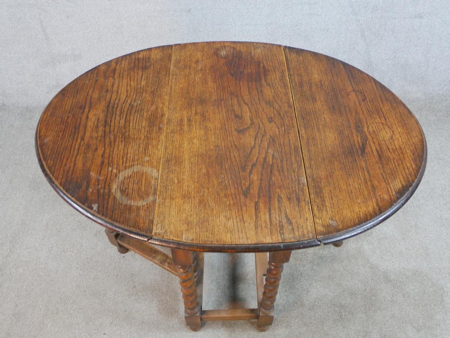 An early 20th century oak drop leaf gate leg table, raised on barley twist supports terminating in - Image 2 of 5