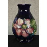 An early 20th century Moorcroft pottery baluster vase, tube lined in the Clematis pattern, impressed