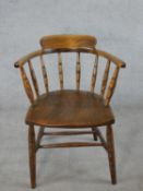 An early 20th century elm and oak Captain style chair, with turned spindles, raised on turned