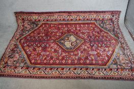 A large 20th century red ground Persian woollen carpet with central lozenge with geometric and