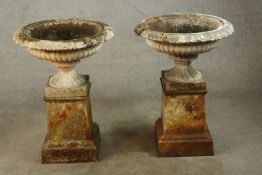 A pair of early 20th century painted cast iron urn shaped garden planters, raised on tapering square