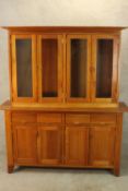 A contemporary, possibly cherrywood, kitchen dresser, with four glass panel doors above four short