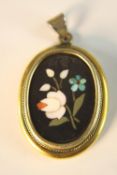 An early 20th century rolled gold framed pietra dura pendant with floral design.