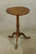 A 19th century circular topped oak tilt top wine table with turned central column raised on three