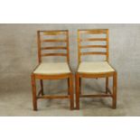 A pair of early 20th century oak framed ladder back chairs, raised on carved supports with drop in