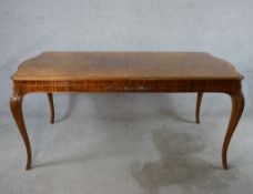 An early 20th century walnut and mahogany veneered pull out dining table raised on cabriole