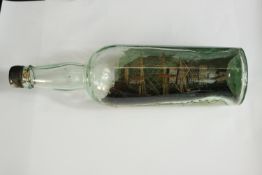 An early 20th century three masted ship in a clear glass bottle. H.30 Dia.8cm.