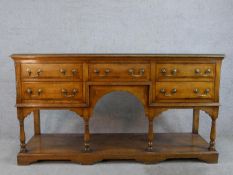 A 20th century oak five drawer sideboard with brass swing handles, raised on turned support with