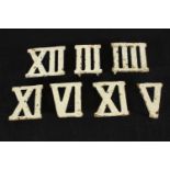 Seven painted cast iron Roman numerals. H.3.5 W.9 D.8.5cm. (largest)