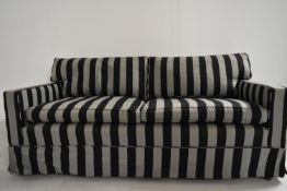A contemporary two seater sofa upholstered in grey and black fabric, some stains and fading to right