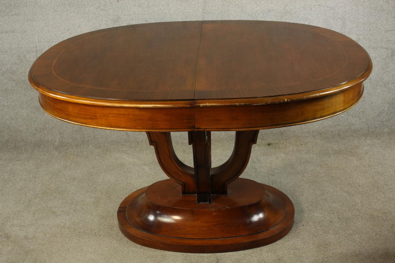 A 20th century mahogany pull oval extendable table, on four carved trumpeting supports terminating