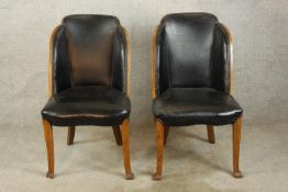 A pair of walnut and black leather Art Deco style chairs raised on tapering supports terminating